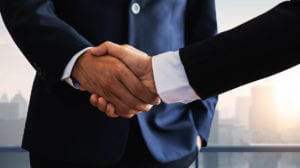 Two men in suits shake hands