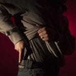 Man with hand on gun in his waistband