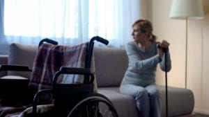 Woman holding onto cane with wheelchair in foreground