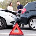 Two drivers examining car body damages after rear end accident