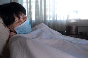 Woman with coronavirus lays down with mask over face