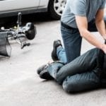 Pedestrian helping a victim of an accident next to a broken bike