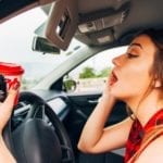 Woman applying mascara while inside her car