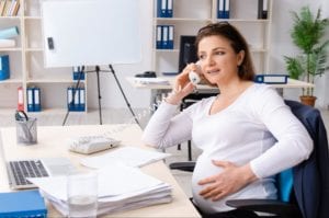 Pregnant woman talking over the phone in her office