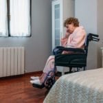 Senior woman sitting in a wheelchair inside her room