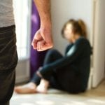 Man with a clenched fist and a woman sitting on the floor