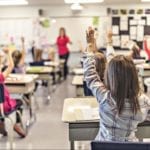 Students raising their hands in class