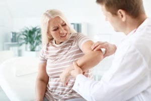 workers compensation shoulder injury settlements: Doctor checking a patient's arm for injury